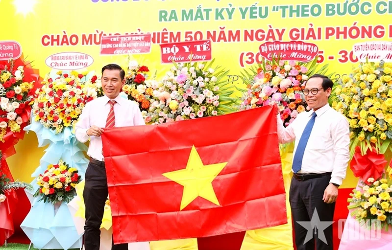 Tiến sĩ Phạm Anh Thắng, Phó chánh Văn phòng Bộ Nội vụ (bên phải) trao tặng Quốc kỳ của Bộ Nội vụ cho đại diện Trường Cao đẳng Đại Việt Sài Gòn.
